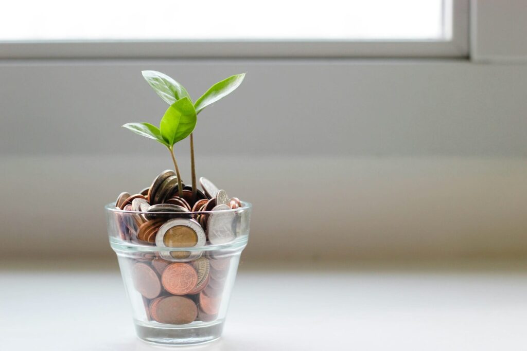 Glazen pot gevuld met munten met een klein plantje dat eruit groeit als symbool voor financiële groei.