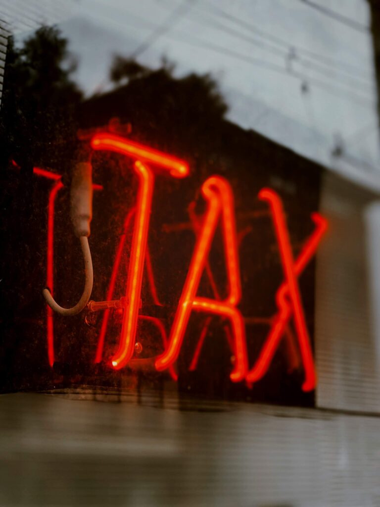 Neon letter met tax erop als symbool voor belastingen bij emigratie.
